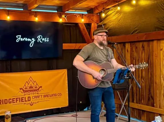 Jeremy Ross playing acoustic guitar during a live performance.